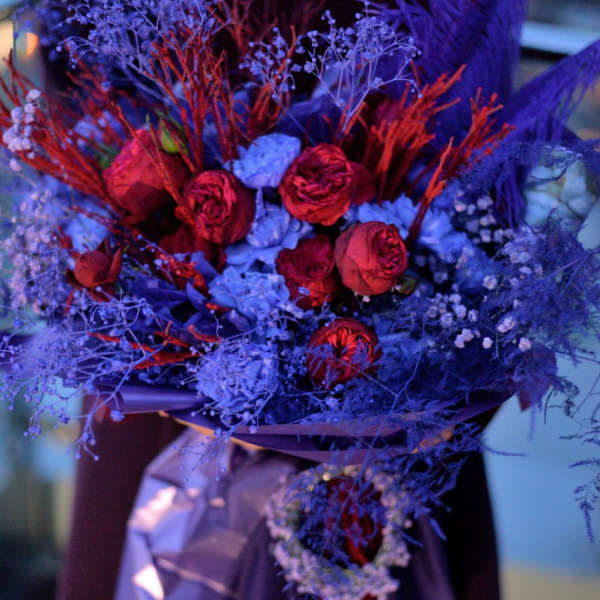 Bouquet of red roses with blue filler flowers and purple wrapping
