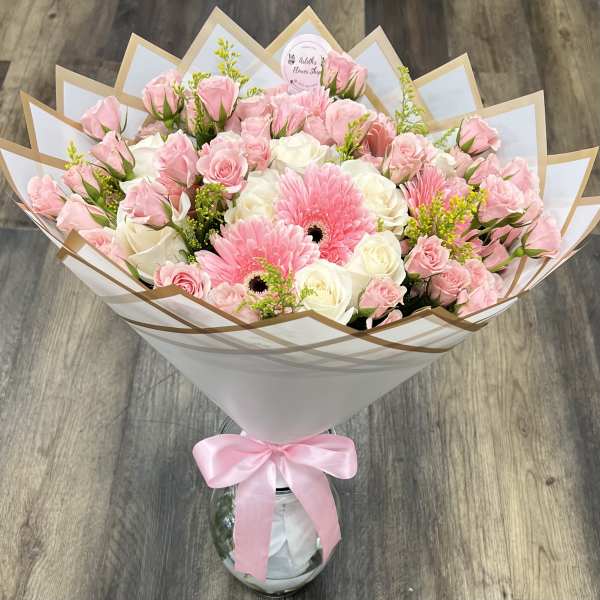 Pink and white rose bouquet with two pink gerbera daisies in a glass vase