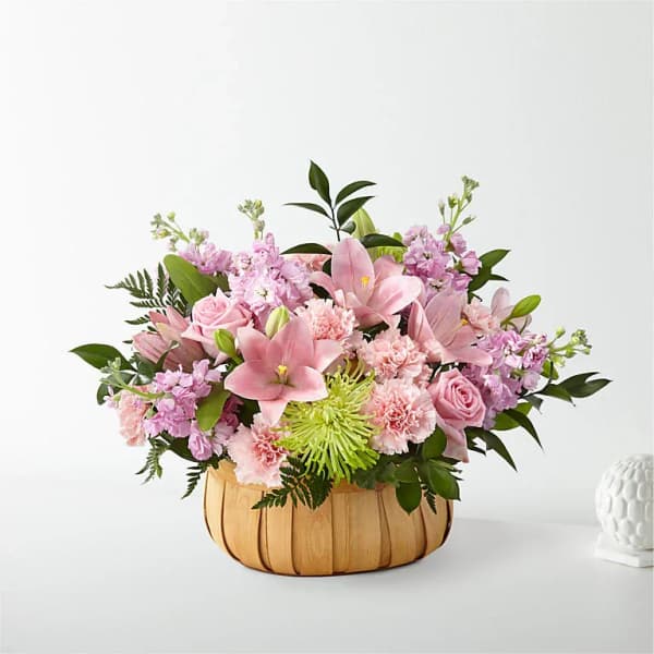 Pink floral arrangement in a woven basket with roses and lilies