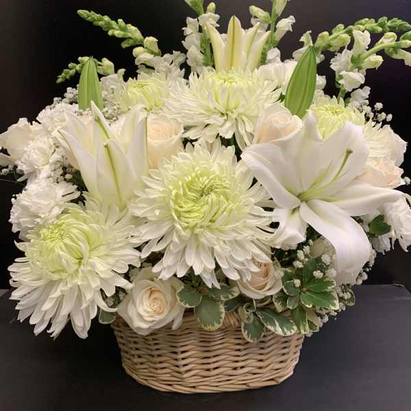 White lilies and chrysanthemums arranged in a wicker basket