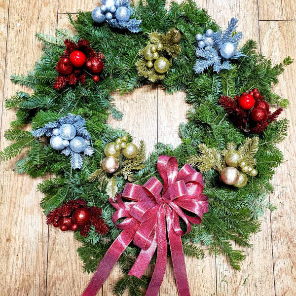 Christmas wreath with colorful ornaments and a pink ribbon bow