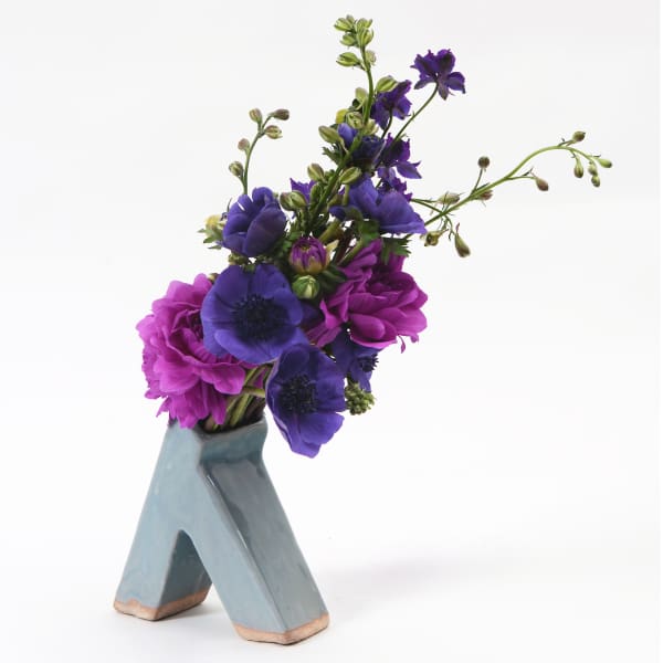 Purple and magenta flowers arranged in a blue ceramic vase