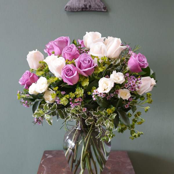 Pink and white roses arranged in a clear glass vase