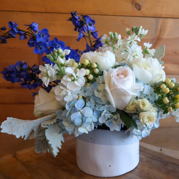 White and blue floral arrangement in a white container