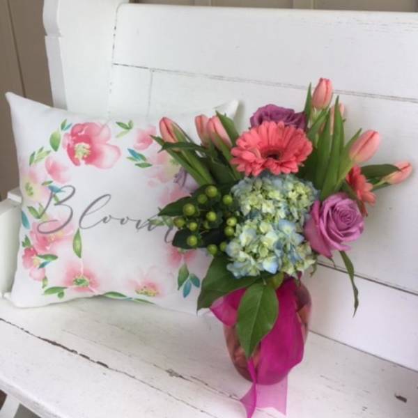 Bouquet with pink tulips, roses, and hydrangea beside a floral pillow
