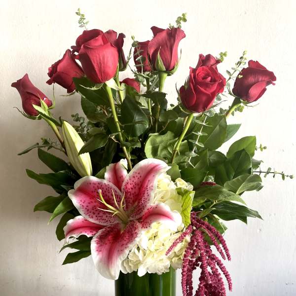 Bouquet of red roses and pink lilies in a tall green vase