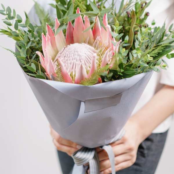 Pink protea bouquet wrapped in gray paper