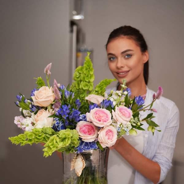Mixed bouquet in a glass vase with pink roses and blue flowers