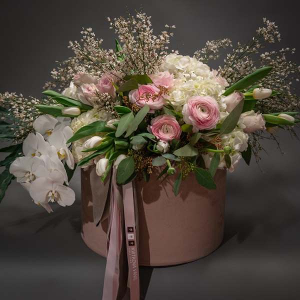 Pink and white floral arrangement in a round blush box with ribbon