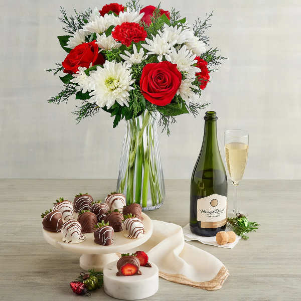 Bouquet of red roses and white daisies in a glass vase with champagne and chocolates