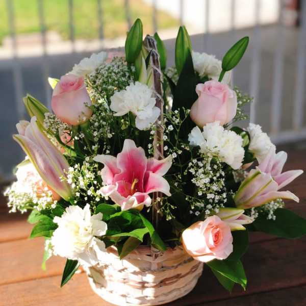 Basket arrangement of pink lilies, roses, and white carnations