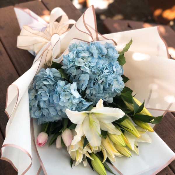 Blue hydrangeas and white lilies wrapped in white paper