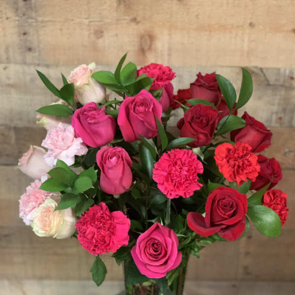 Bouquet of pink and red roses with carnations in a glass vase