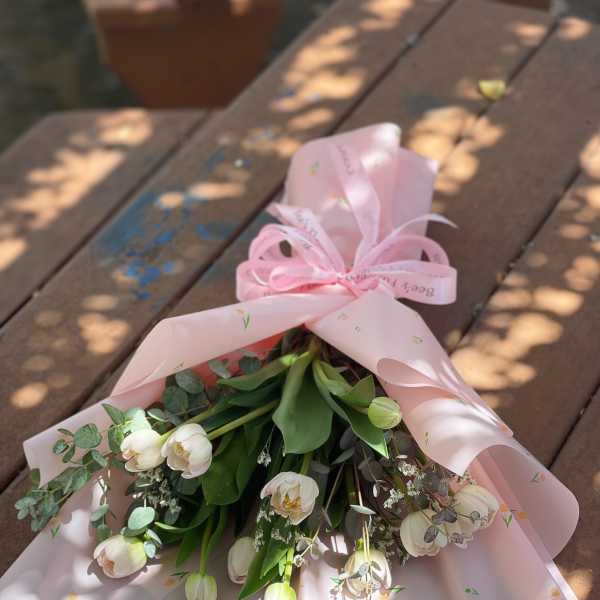 Bouquet of white tulips wrapped in pink paper with a ribbon