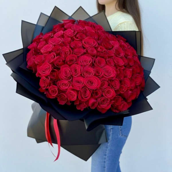 Large bouquet of red roses wrapped in black paper with a red ribbon