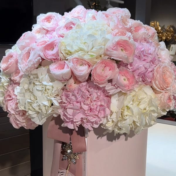 Pink and white flower arrangement in a round pink box with ribbon
