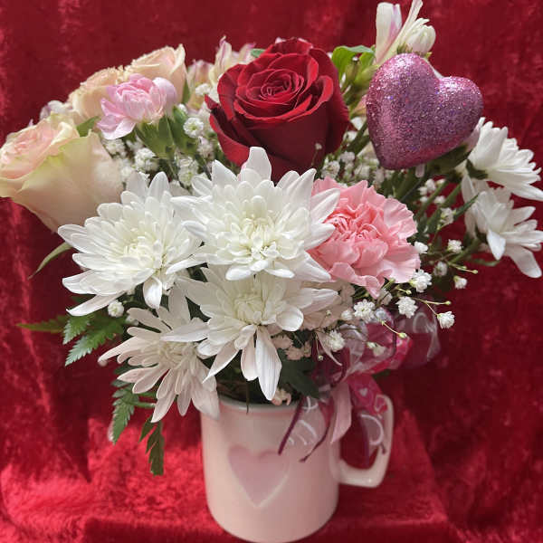 Bouquet of roses, chrysanthemums, and carnations in a white mug with a glitter heart