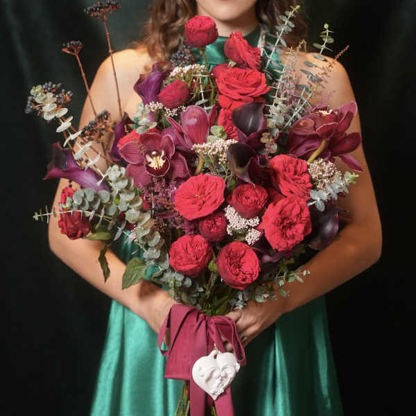 Large bouquet of red roses, purple orchids, and eucalyptus tied with a ribbon