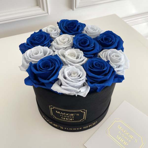 Blue and white roses arranged in a black round box