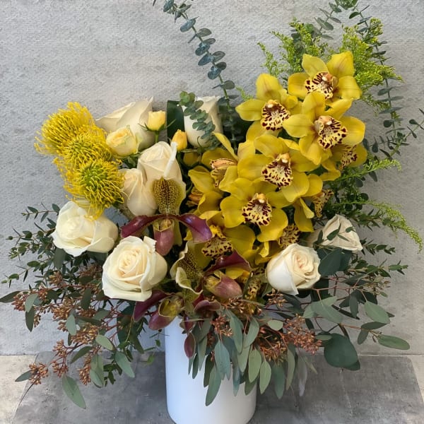 Bouquet of yellow orchids and white roses in a white vase