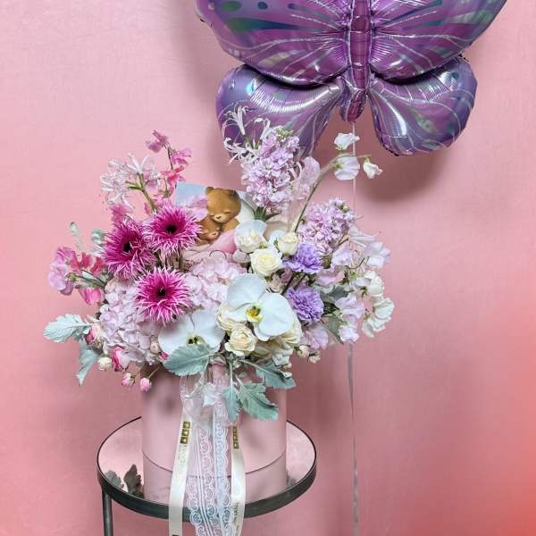 Pink floral arrangement with a purple butterfly balloon