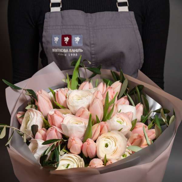 Bouquet of pale pink tulips and white ranunculus in pink wrap