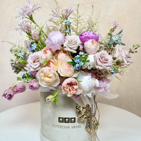 Pastel bouquet of roses and peonies in a round hatbox