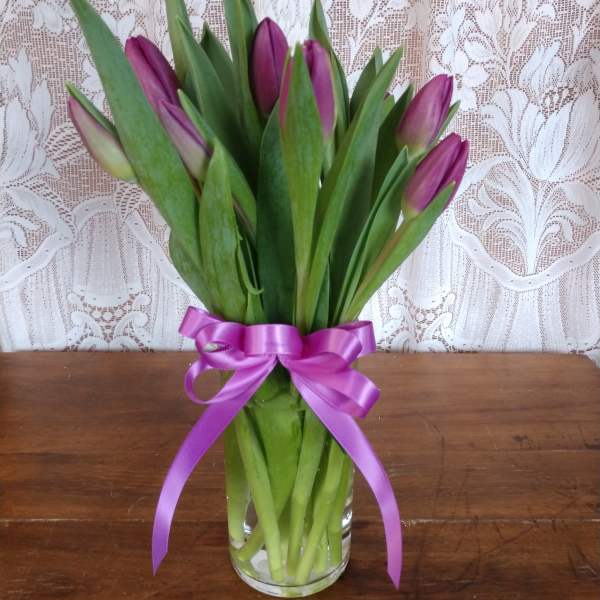 Purple tulip bouquet tied with a satin ribbon in a clear glass vase