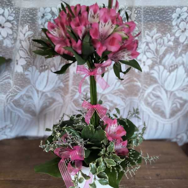 Pink alstroemeria arrangement in a white container with ribbon
