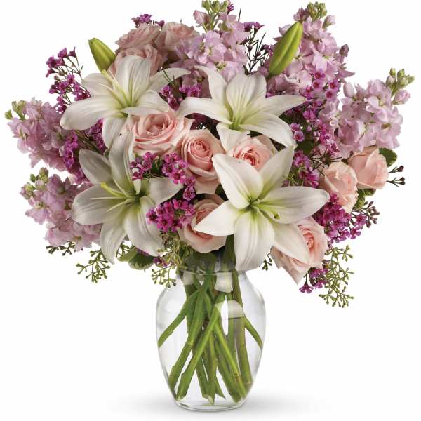 Pink roses and white lilies arranged in a clear glass vase