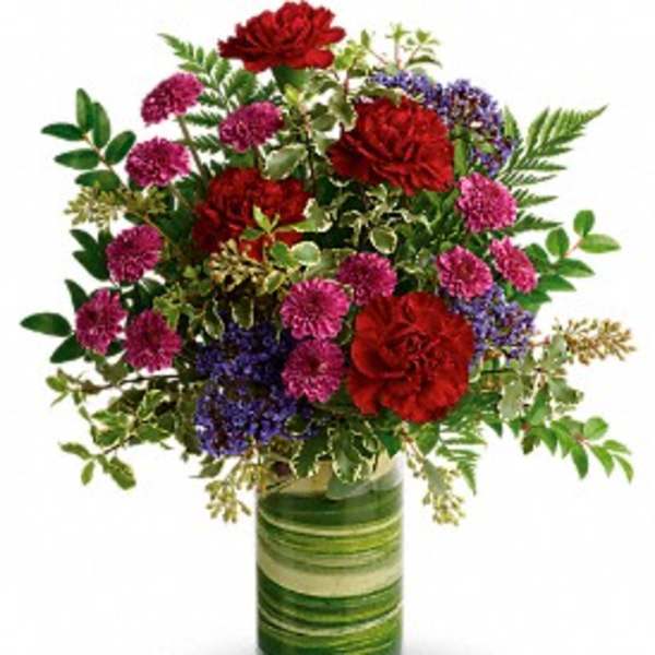 Mixed red and purple flowers in a green striped glass vase