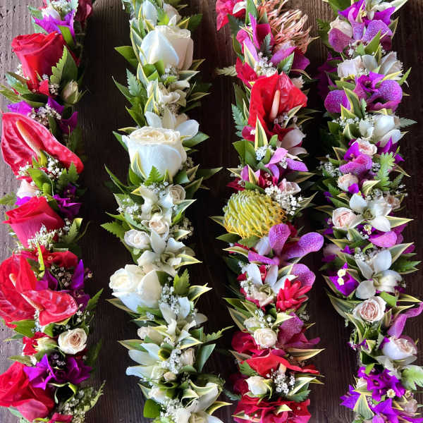 Set of four colorful floral garlands with red, white, pink, and purple blooms on a wooden surface