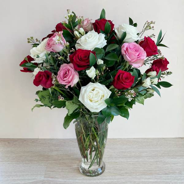 Bouquet of red, pink, and white roses in a clear glass vase