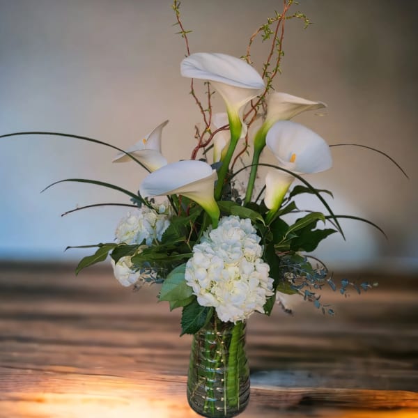 White calla lilies and hydrangeas in a glass vase