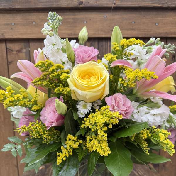 Mixed bouquet in a glass vase with yellow, pink, and white flowers