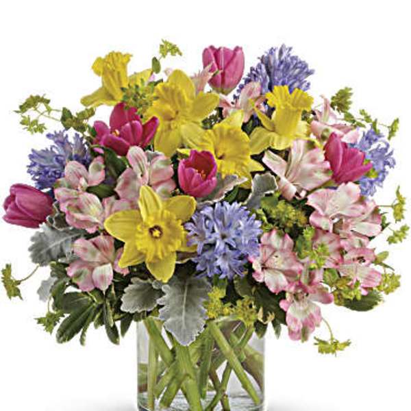 Colorful bouquet of tulips and daffodils in a clear glass vase