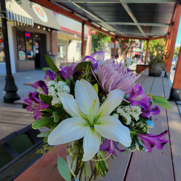 Bouquet of white lilies and purple flowers in a glass vase