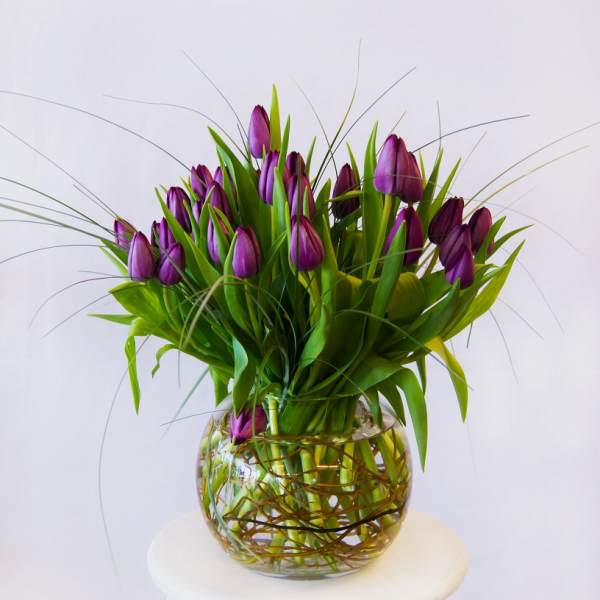 Purple tulips arranged in a round glass vase