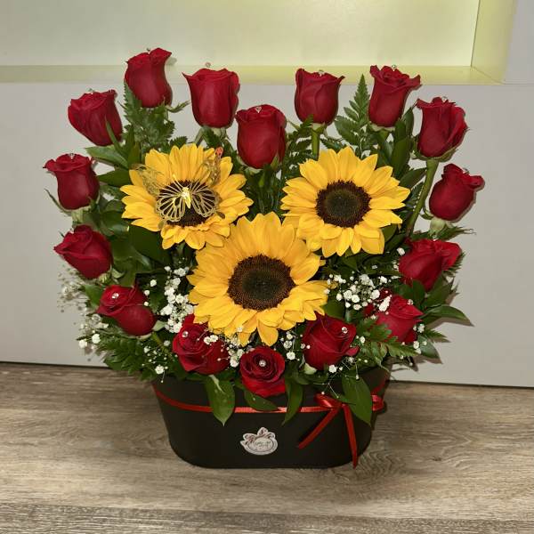 Red roses and yellow sunflowers arranged in a black box with a red ribbon.