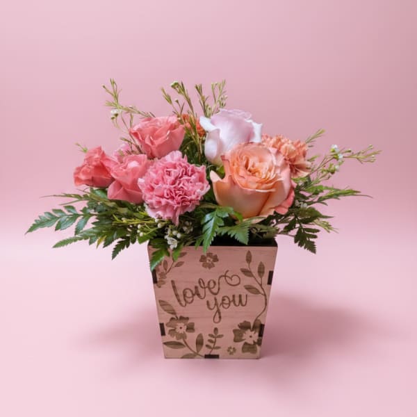 Pink and peach roses in a wooden planter with "love you" text