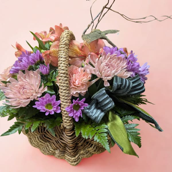 Basket of pink and purple flowers with a ribbon bow