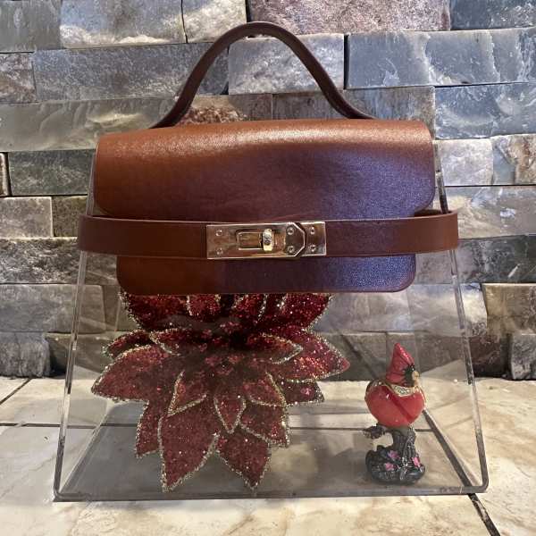 Brown handbag with a glittery red flower charm and small cardinal figurine