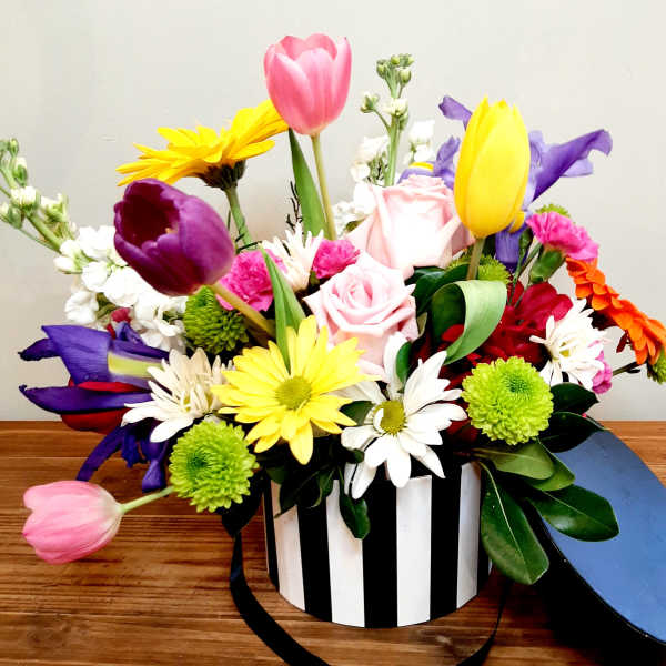 Mixed bouquet in a black-and-white striped box with pink, yellow, purple, and white flowers