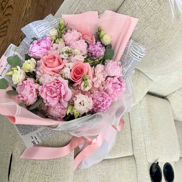 Pink bouquet of roses and peonies wrapped in pink paper