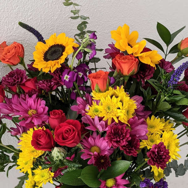 Mixed bouquet with sunflowers, roses, and purple daisies