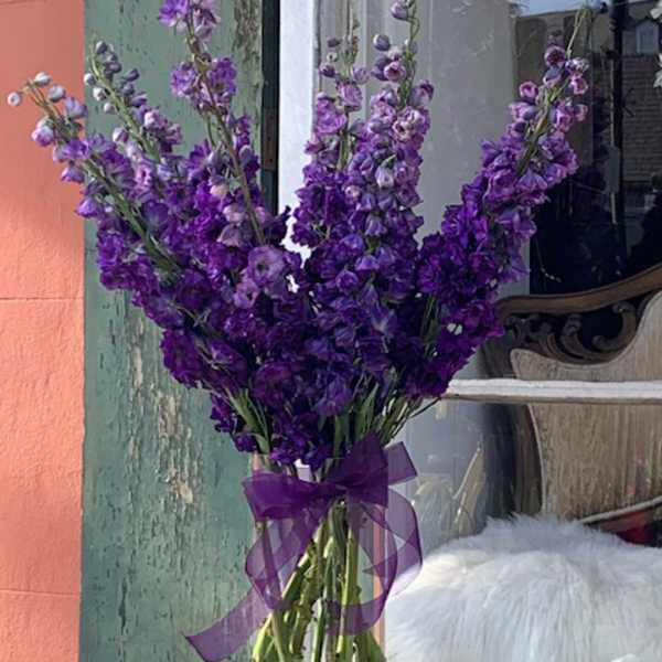Purple flower bouquet in a clear glass vase with a ribbon bow