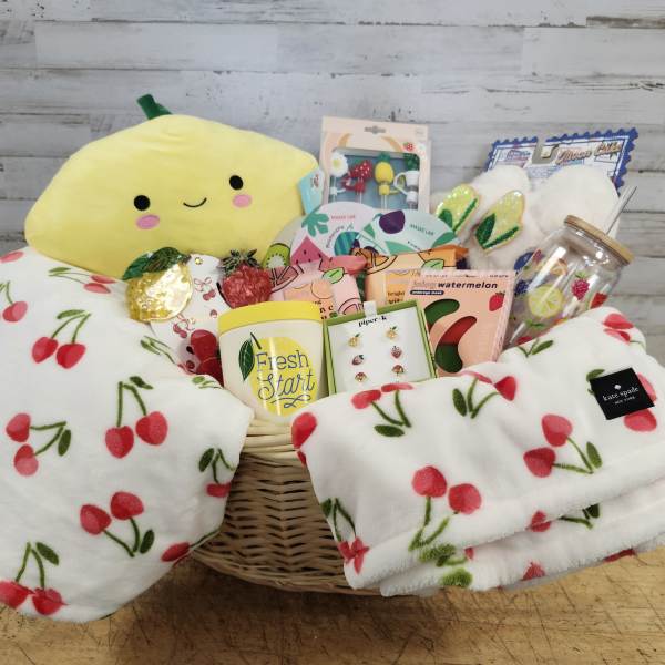 Gift basket with a plush lemon, cherry blanket, and assorted self-care items