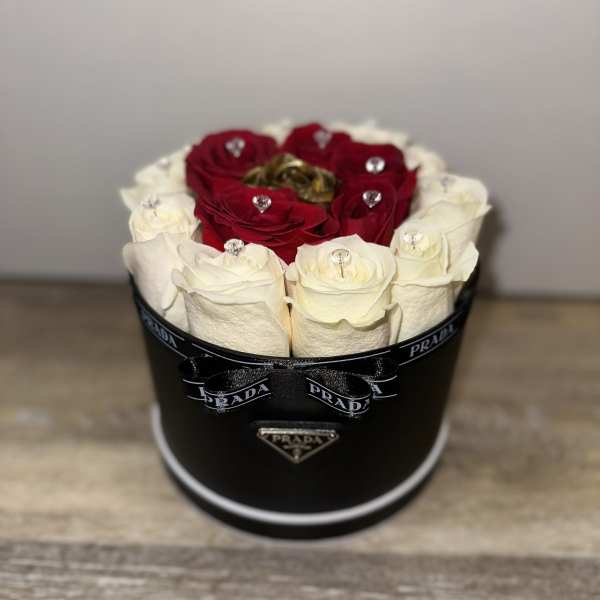 Red and white roses arranged in a black round box with a ribbon