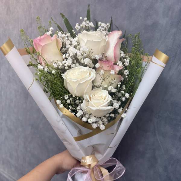 Bouquet of white and pink roses with baby's breath in white wrap
