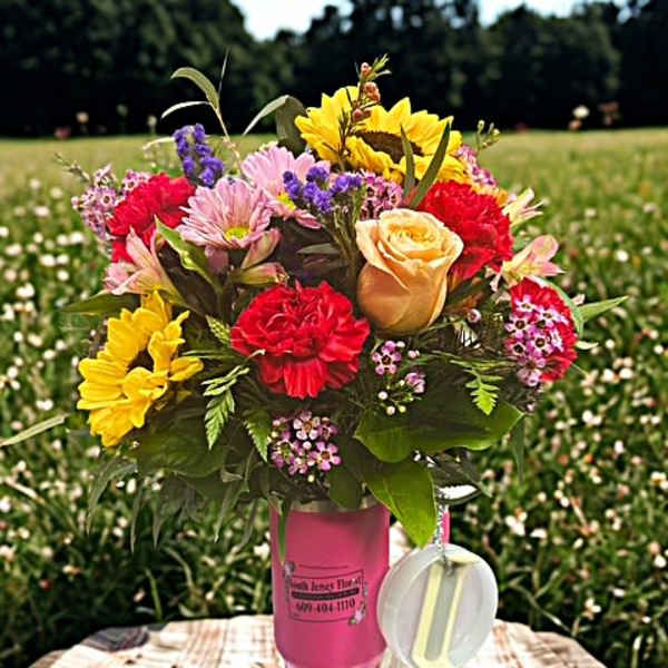 Mixed bouquet in a pink cup-style vase with a hanging tag